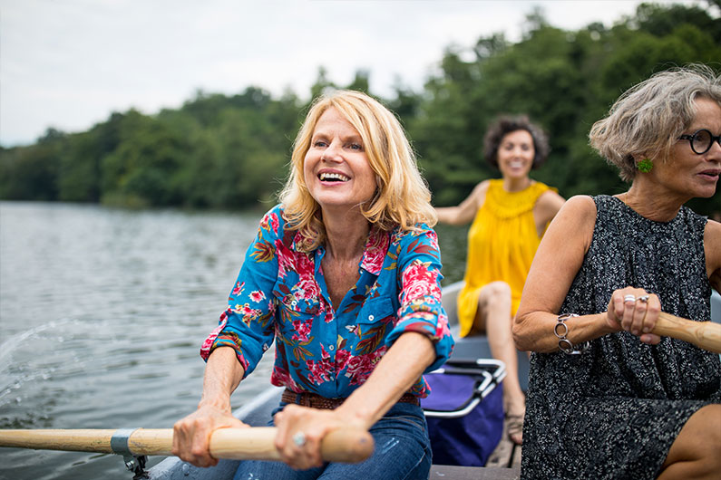 Older women rowing on a boat in the middle of a lake