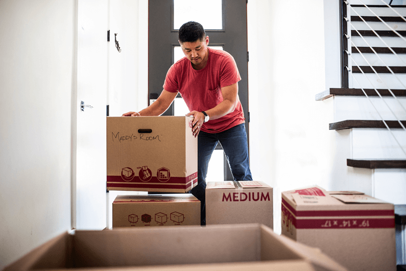 A man stacks cardboard moving boxes as he settles into a new home.