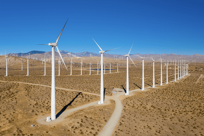 Aerial view of windmills in an open desert field producing wind energy.