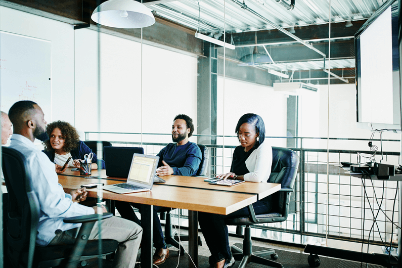 A group of business professionals sit at a table and discuss hedging strategies to manage interest rate risks.