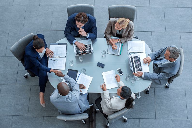 Executives gather around a large conference table and discuss how to manage an unsolicited M&A offer.