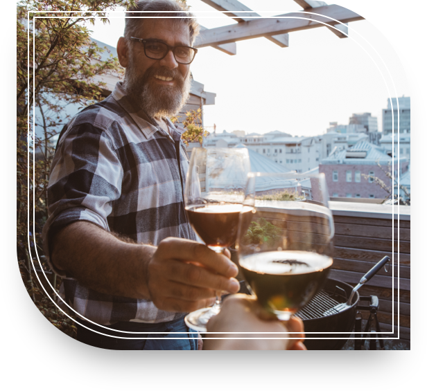 Smiling man standing outdoors with a glass of wine in his hand