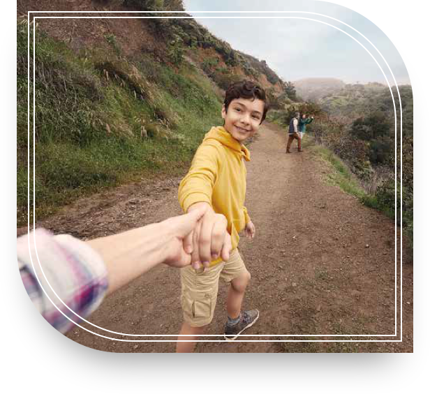 A kid in a yellow shirt on a hike holding his grandmother’s hand. She is enjoying her day thanks to her investment strategies.