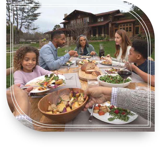 A family sharing a meal outside their house discussing private banking.