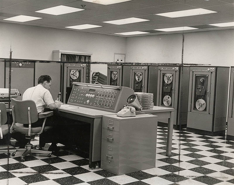 A man sitting in front of a 1960s computer