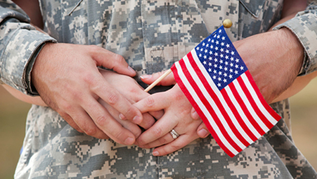 A couple holds a small American flag through their fingers.