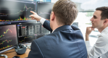 Two men pointing at a computer with graphs showing corporate trust services.