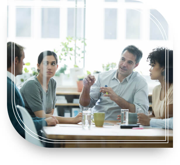 A meeting of four people discussing investment management around a conference table.