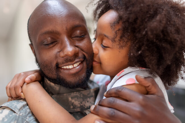 A young girl smiles while hugging her father.