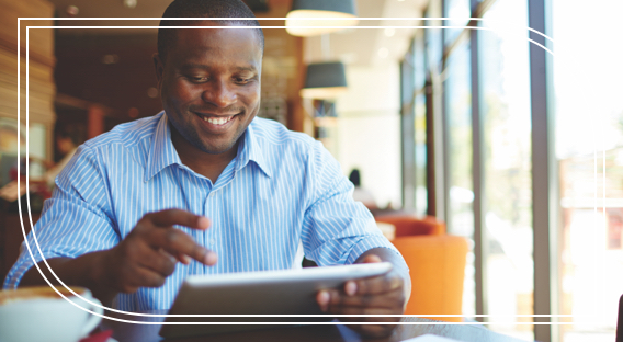 A smiling man holding an ipad at a cafe