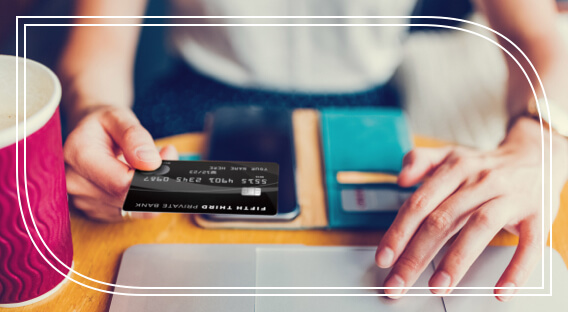 A person holding a Fifth Third Private Bank Mastercard above their laptop.