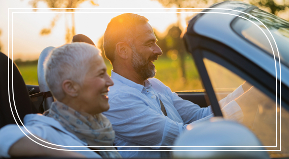 Middle-aged man and woman driving a car and smiling